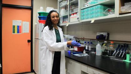 Ashley Crawley is in a lab wearing a lab coat and smiling. 