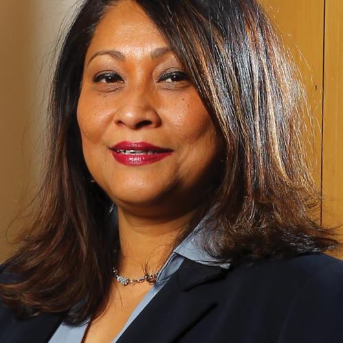 Piyushimita has shoulder length straight brown and is wearing a black jacket and a blue collared shirt