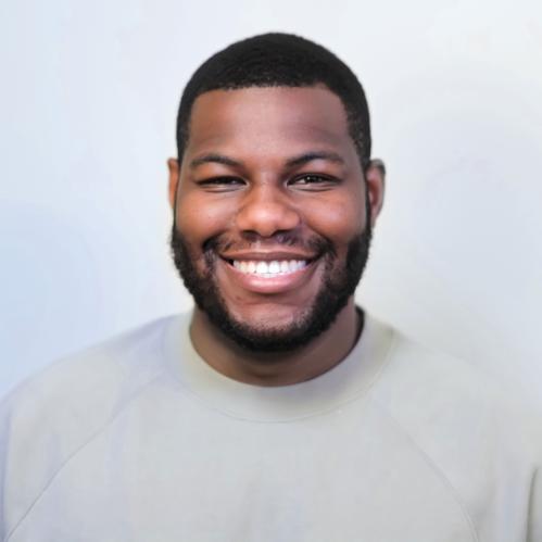 Andrew is a young african american male with short hair. He is smiling and wearing a grey sweatshirt.