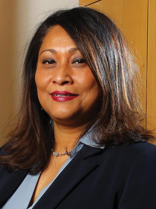 Piyushimita has shoulder length straight brown and is wearing a black jacket and a blue collared shirt