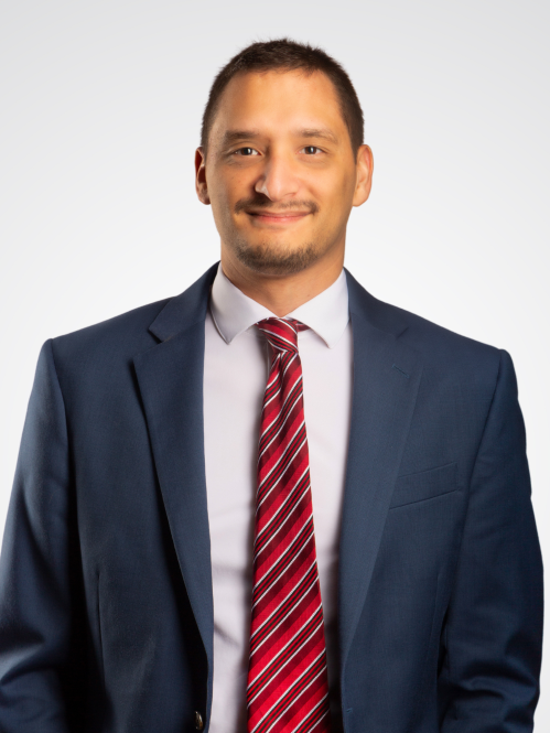 Man in this 30s wearing a blue suit and red striped tie.