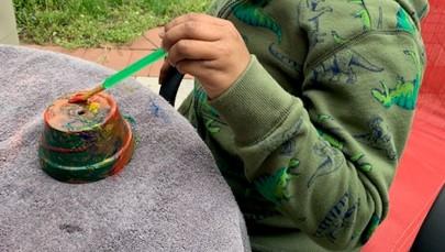 Child's hand painting a flower pot
